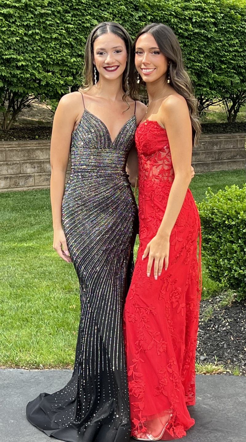 Two girls in prom dresses, sparkly black and red lace gowns